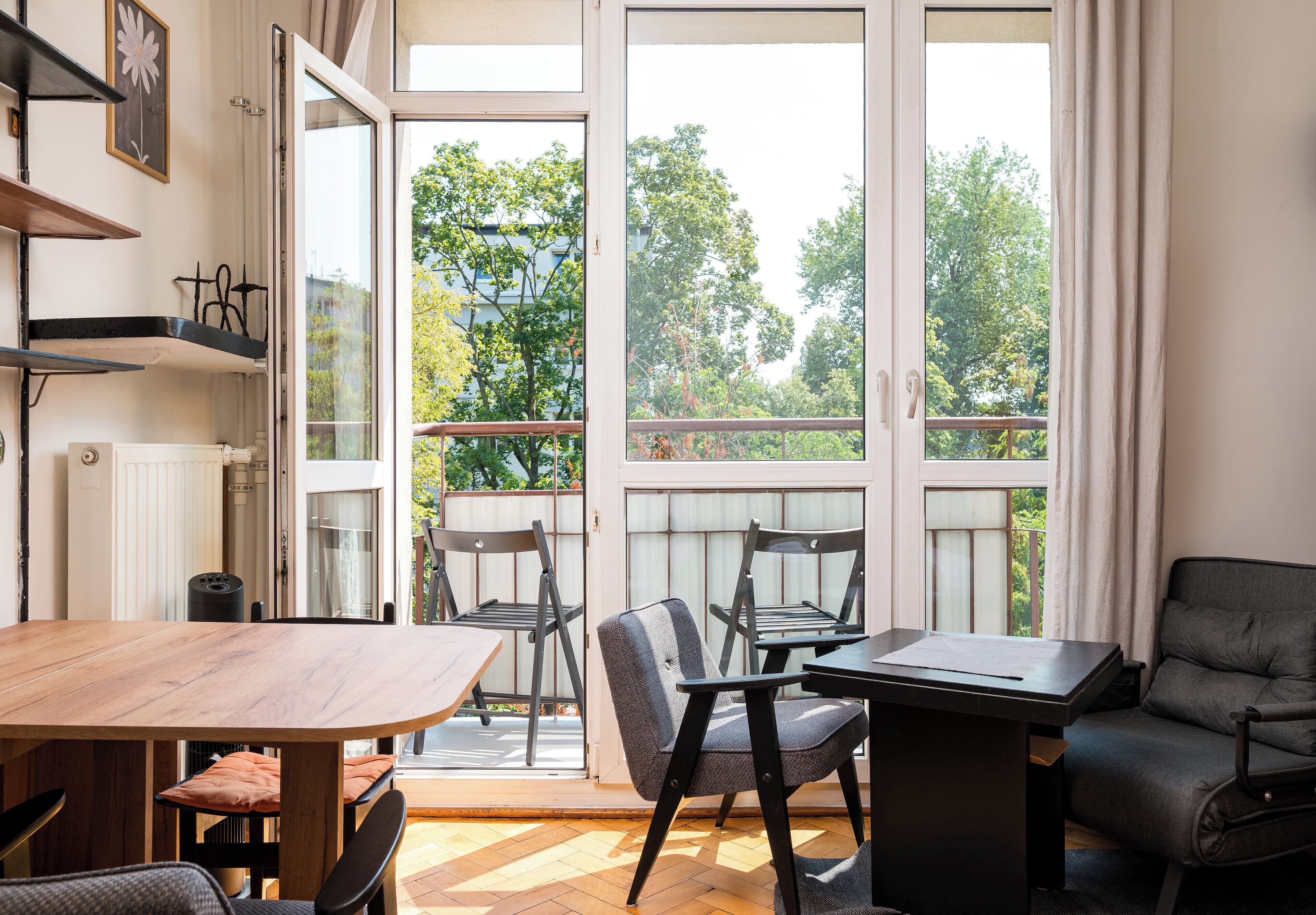 Un interior moderno con comedor, sofá y vistas a árboles a través de amplios ventanales.