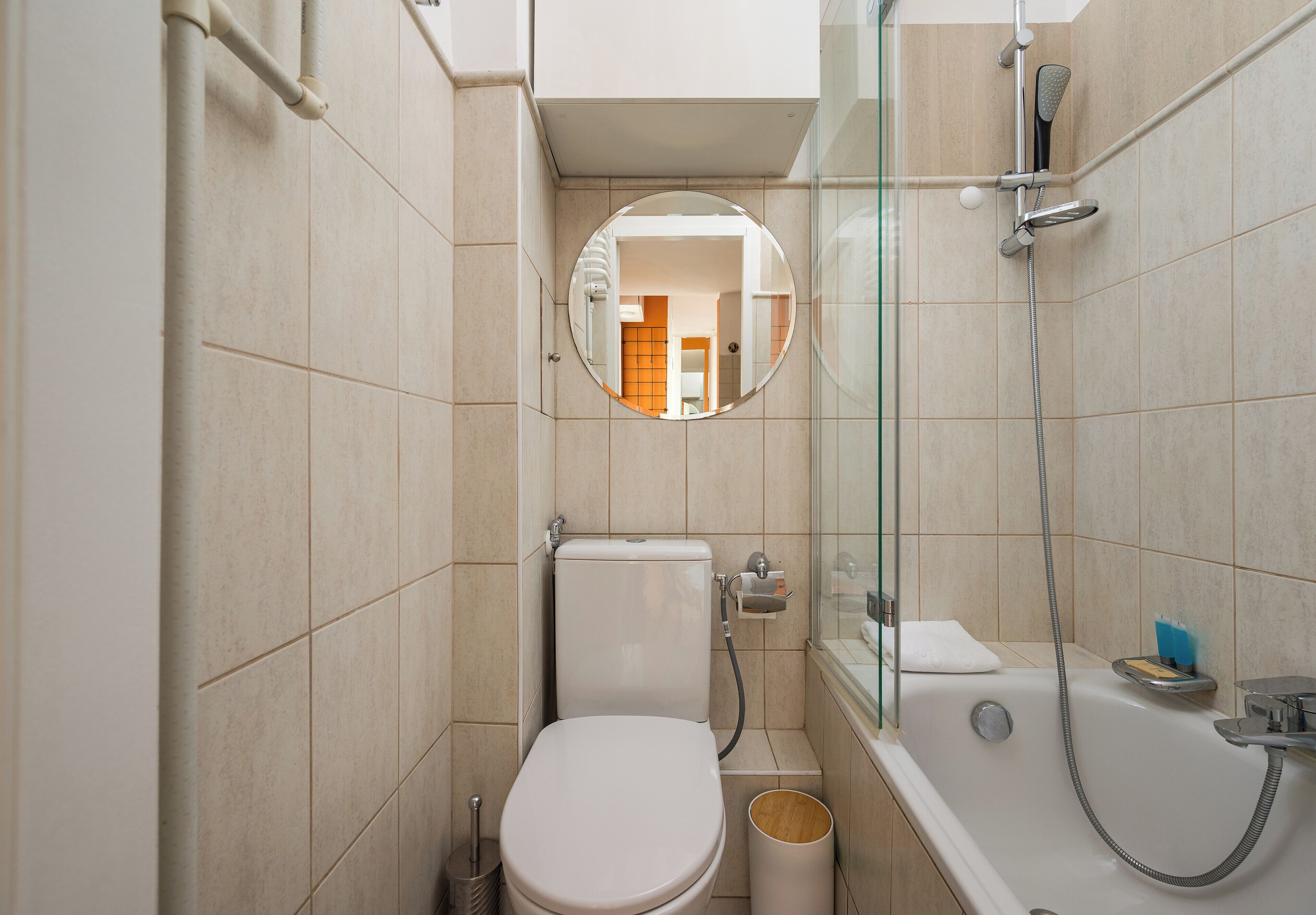 Uma casa de banho compacta com sanita, cabine de duche com vidro e banheira.