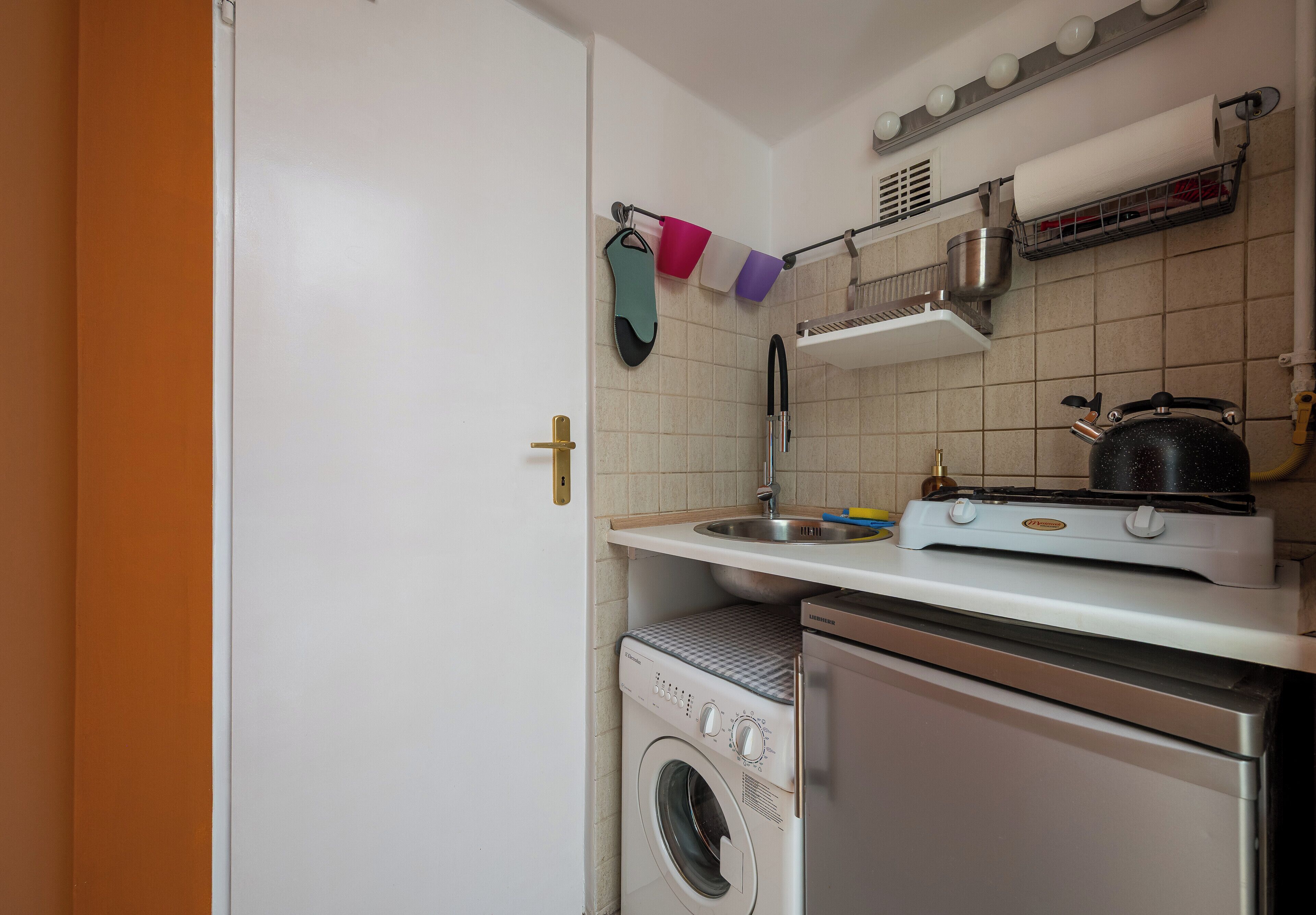 Una cocina compacta con lavadora, estufa y lavabo.