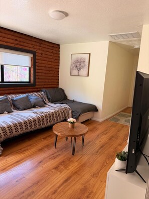 Una sala acogedora con un sofá, una mesa redonda de centro y un televisor de pantalla plana.