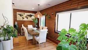 Ein Essbereich mit einem Holztisch und -stühlen, umgeben von Topfpflanzen und einer Weltkarte an der Wand.