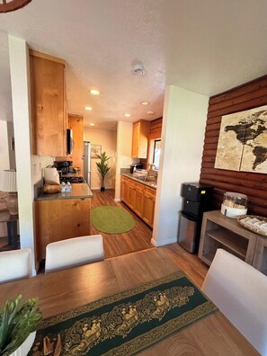 Un espacio habitable compacto con comedor, kitchenette y una pequeña zona de estar.