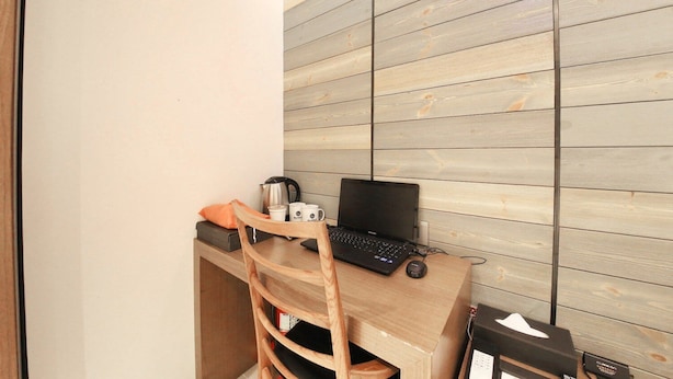 Un petit espace de travail comprenant un ordinateur portable, une machine à café et une chaise.