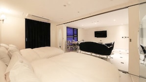Une chambre à coucher moderne avec un grand lit, une baignoire noire et un téléviseur fixé au mur.