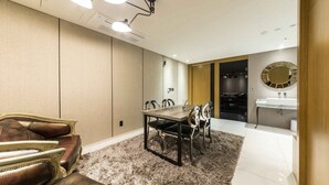 Une chambre d’hôtel moderne dotée d’un coin repas, d’un grand miroir et d’une salle de bain avec un lavabo.