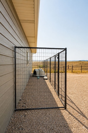 A fenced outdoor area with a gravel path leading to a covered pet area. - Ultimate Family Getaway - Hot Tub • Gym • Game Room • Amazing Views (Hermosa)
