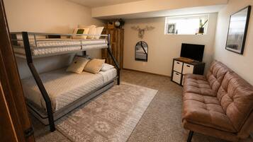 Una habitación con una cama litera, un sofá de cuero marrón, un televisor pequeño y un espejo decorativo.