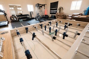 A foosball table in a room with exercise equipment and a motivational poster.