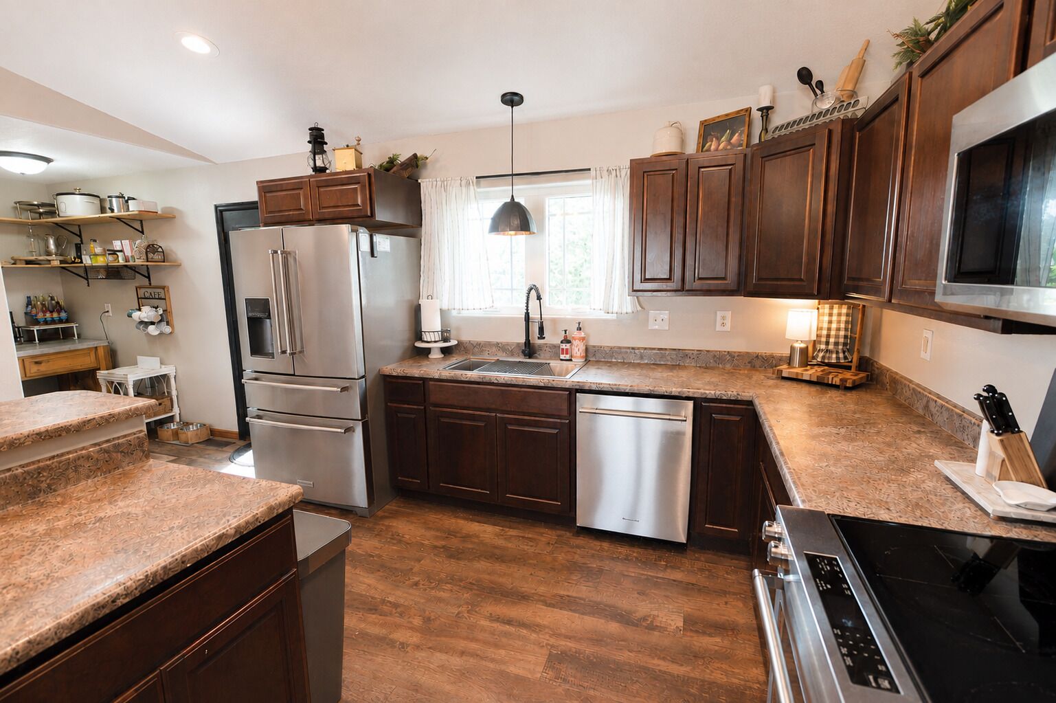 A modern kitchen with stainless steel appliances, wooden cabinets, and a granite countertop.