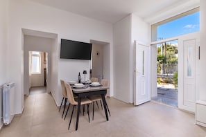 A modern dining area with a table set for four, a flat-screen TV mounted on the wall, and a sliding glass door leading to an outdoor area. - Seaview and Terrace Apartment La Vita, Kostrena, Croatia (Kostrena)
