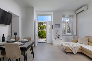 A modern living room with a dining area, a sofa, a TV, and a view of the outside. - Seaview and Terrace Apartment La Vita, Kostrena, Croatia (Kostrena)