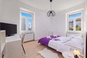 Quarto moderno com cama, escrivaninha, cadeira, abajur e radiador.