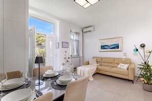 A modern living room with a dining area, a sofa, a painting, and a potted plant. - Seaview and Terrace Apartment La Vita, Kostrena, Croatia (Kostrena)
