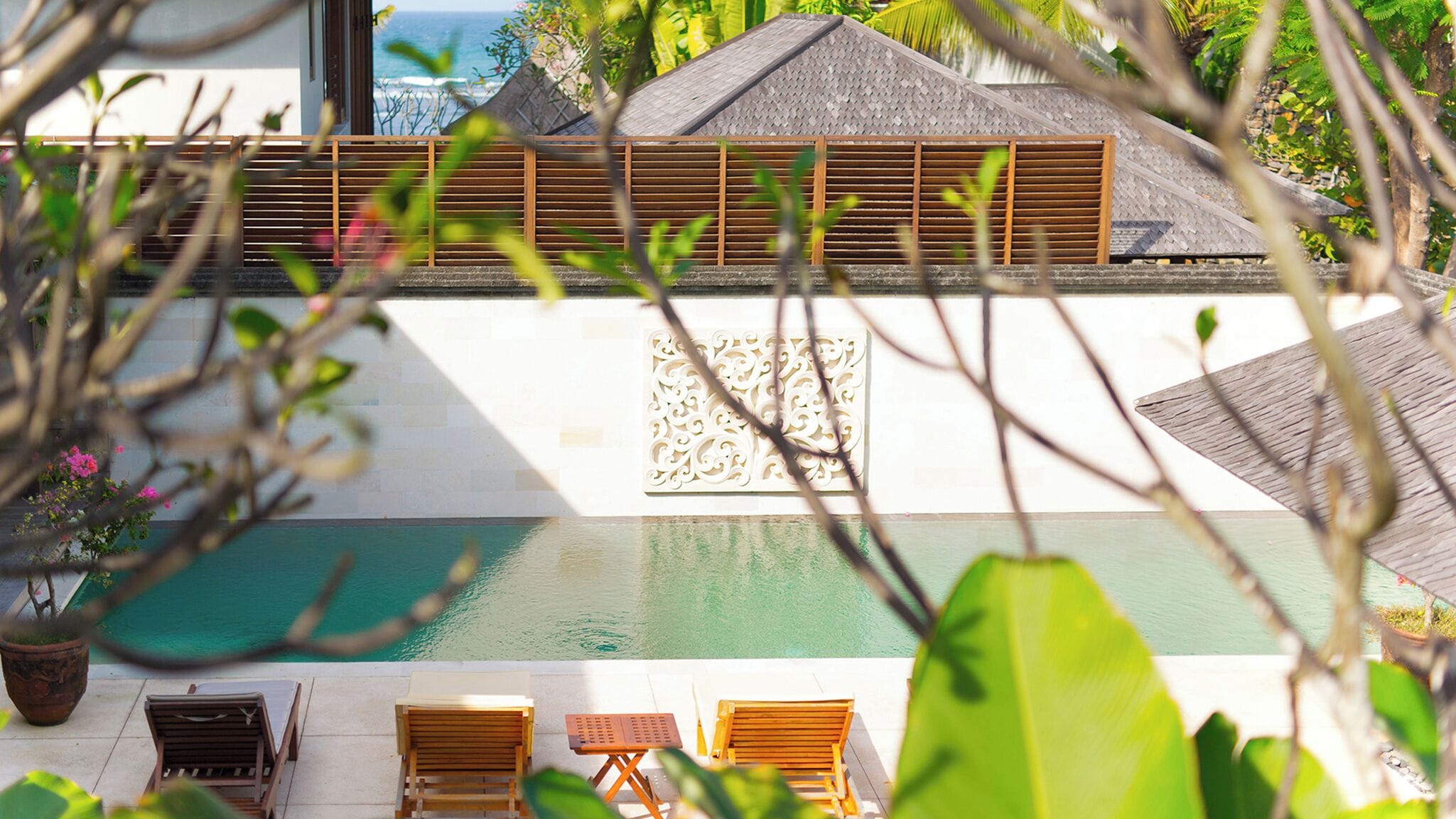 A pool area with lounge chairs and a decorative wall.