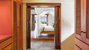 A hotel room with a bed, a window with curtains, and wooden doors. - Bayu Gita Residence (Gianyar)
