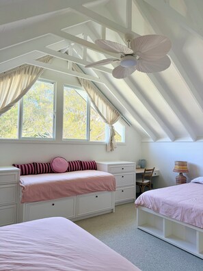 A bedroom with a sloped ceiling, a bed with pink bedding, a desk with a chair, and a window with curtains. - Spacious Avalon Beach family retreat. Walk to beach. (Avalon Beach)
