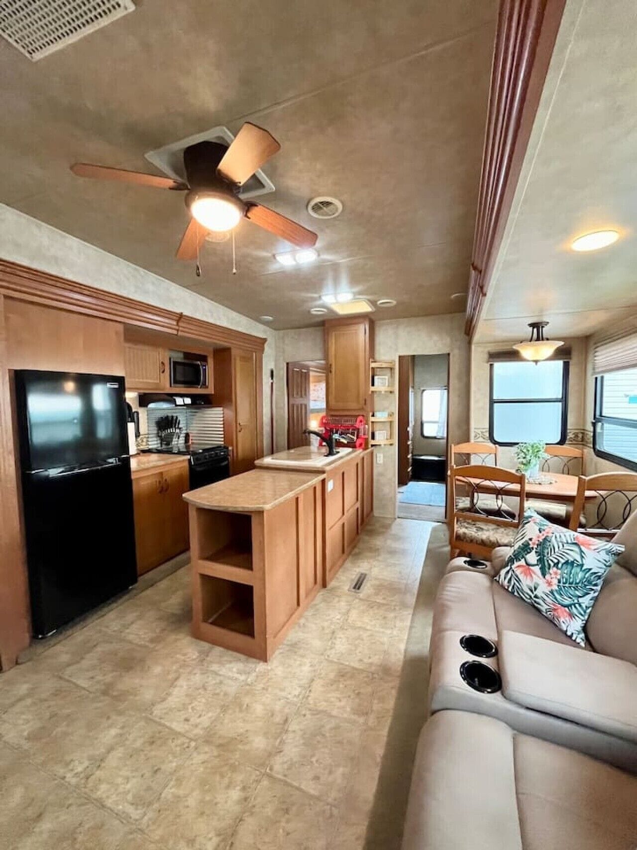 A compact RV kitchen with a refrigerator, microwave, and wooden cabinets.