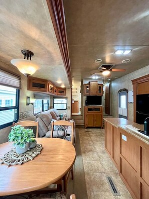 A compact RV interior with a dining area, kitchenette, and seating space. - 1768 Ocean Escape RV (Myrtle Beach)