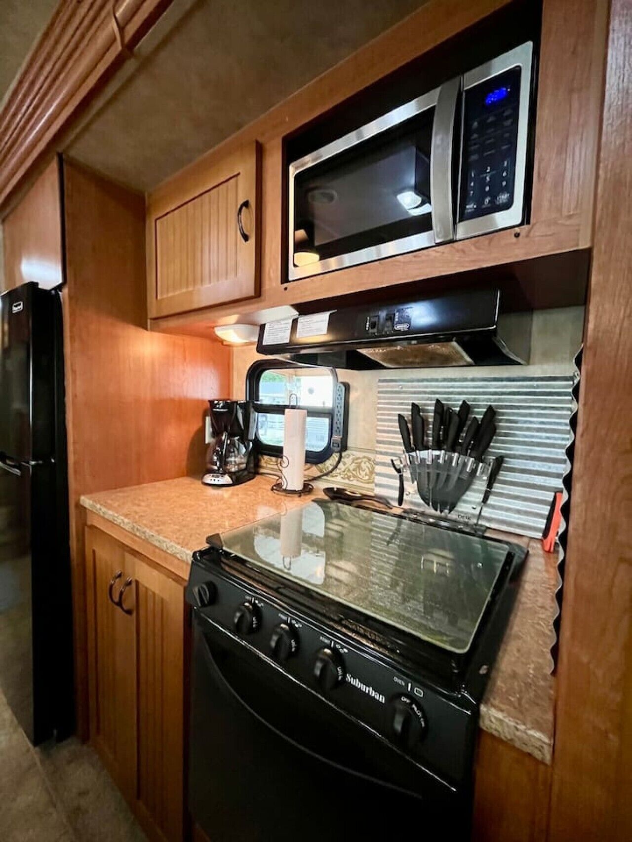 A compact kitchen with a stove, microwave, and refrigerator.