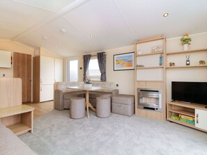 A modern, well-lit room with a dining area, a television, and a bookshelf. - Willow's Retreat by Interhome (Lossiemouth)