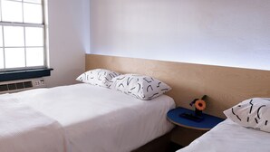 A bedroom with a bed, a nightstand, a window, and a wall-mounted heater. - The Iris Motel - Queen Room (Nashville)