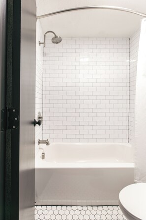 Un baño con una bañera blanca, ducha e inodoro.