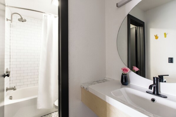 Ein modernes Badezimmer mit einer weißen Badewanne, einem großen Spiegel und einem Waschbecken mit einem schwarzen Wasserhahn.