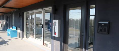 A modern building with large glass doors, a wooden ceiling, and a blue bench outside.