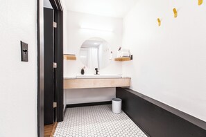 Un baño moderno con lavamanos blanco, espejo y suelo de baldosas hexagonales.