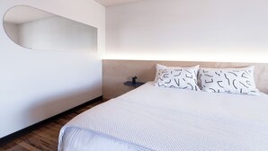 Ein Schlafzimmer mit einem Bett, einem runden Spiegel und einem Nachttisch mit Lampe.
