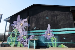 A building with a mural of purple flowers and geometric patterns.