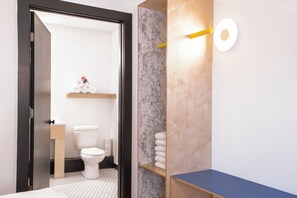 Un baño moderno con inodoro, pared de mármol, estantes de madera y encimera azul.