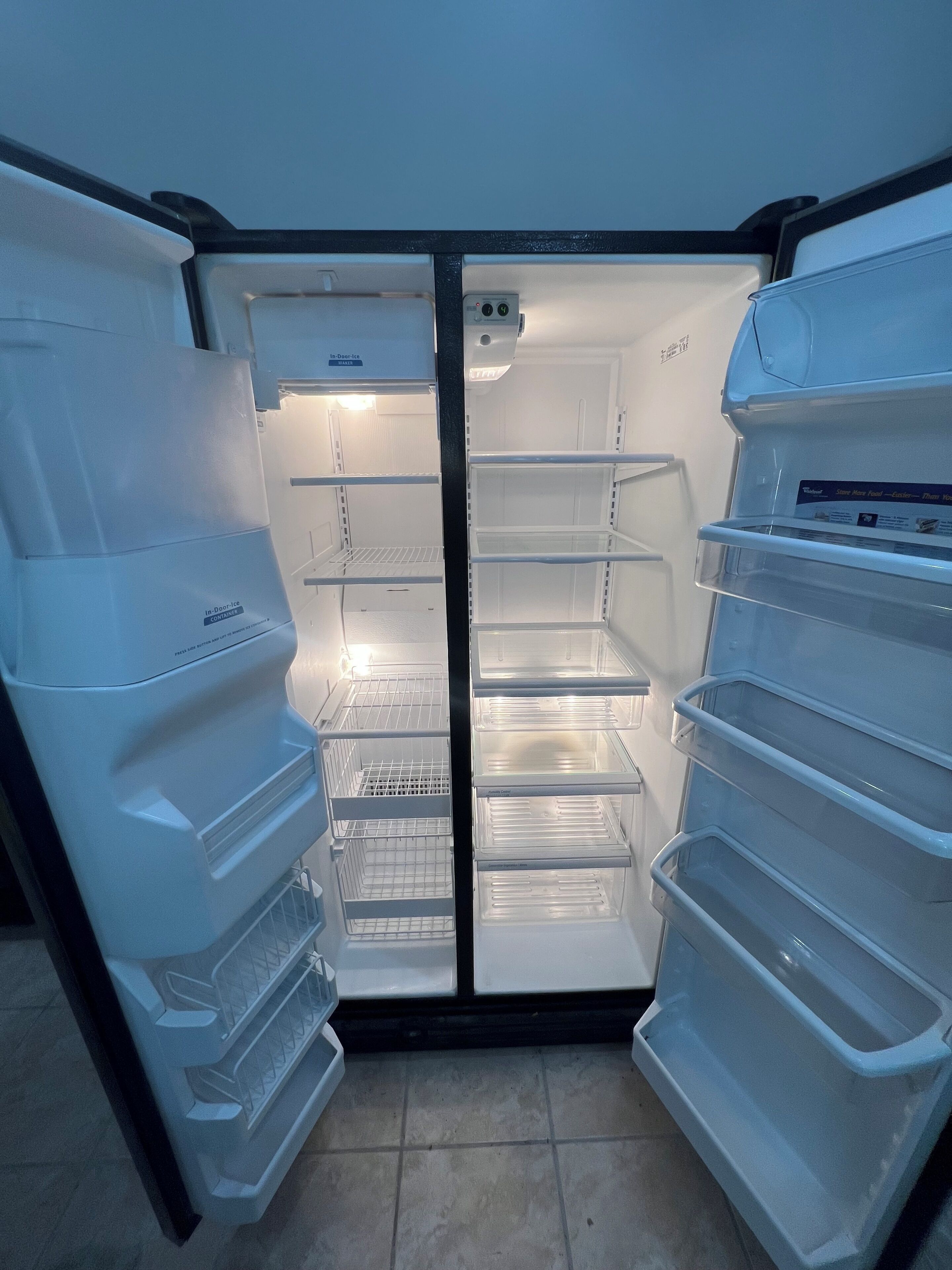 Un réfrigérateur vide, doté de plusieurs étagères et d’un compartiment congélateur.