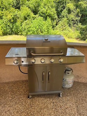 A Char-Broil gas grill with four burners, a side table, and a propane tank.