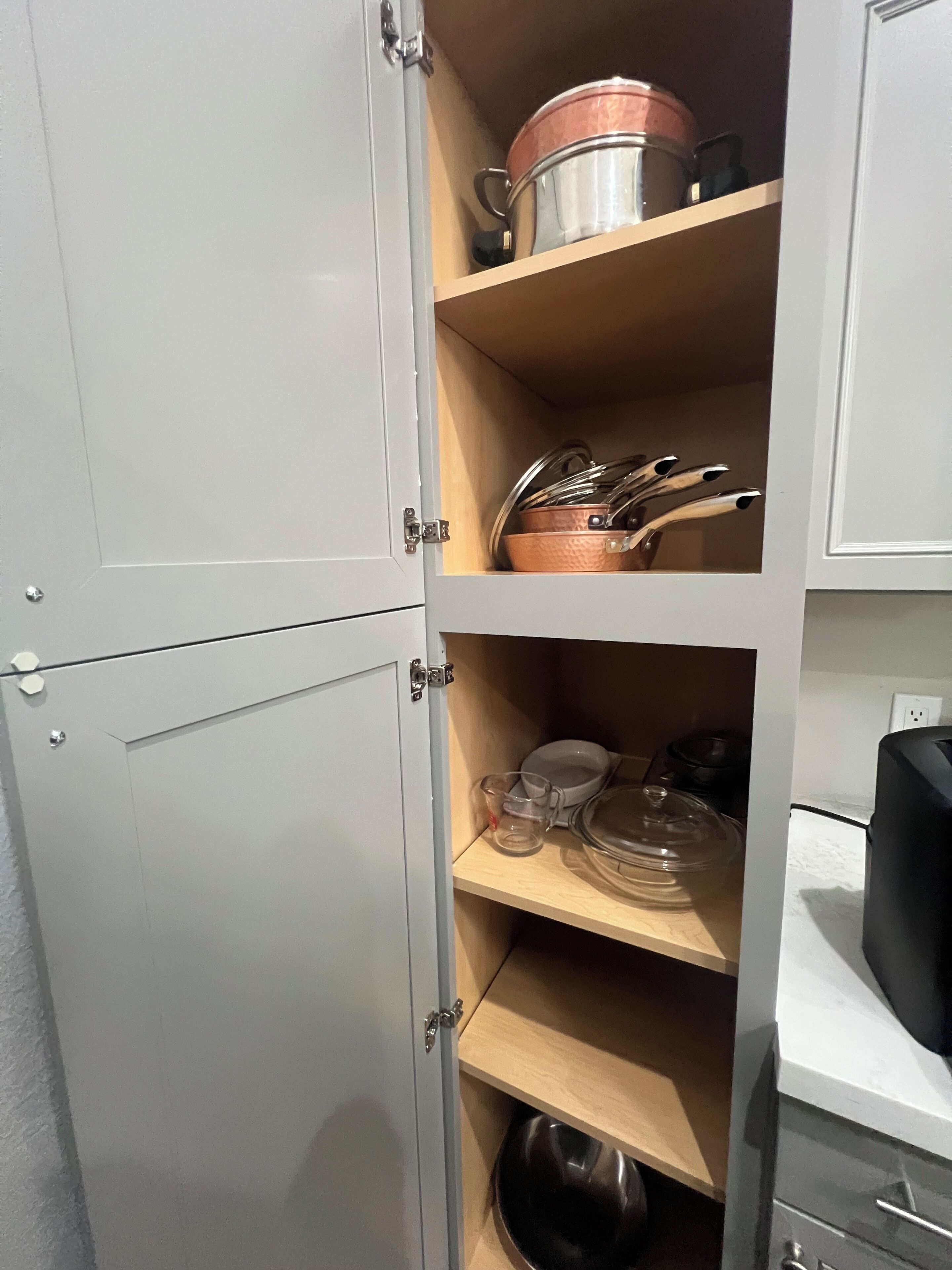 Un meuble de cuisine doté d’étagères où sont rangés des ustensiles de cuisine, une bouilloire et une machine à café.