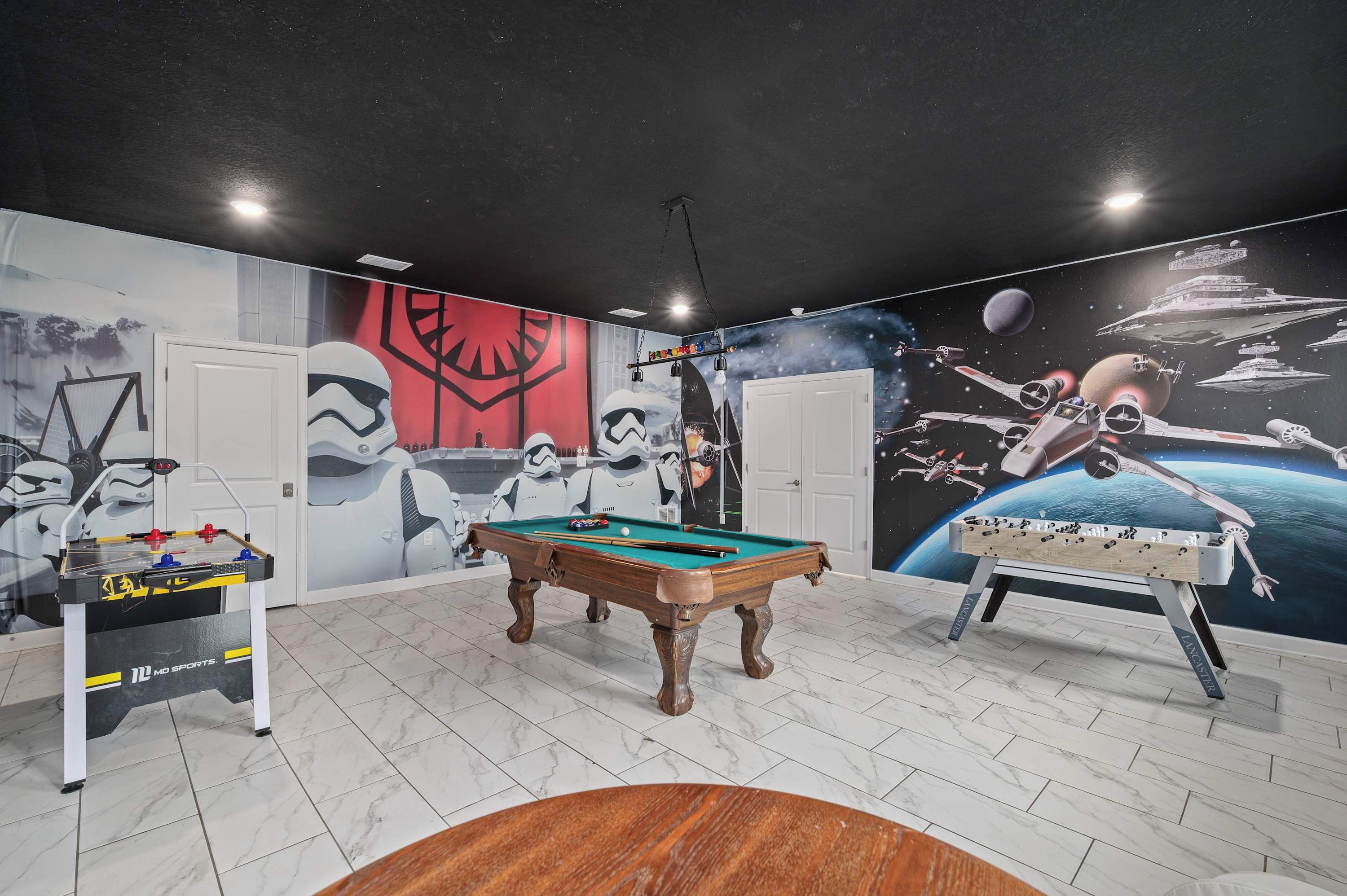 Une pièce équipée d’une table de billard, d’un baby-foot et ornée d’une fresque murale sur le thème de Star Wars.