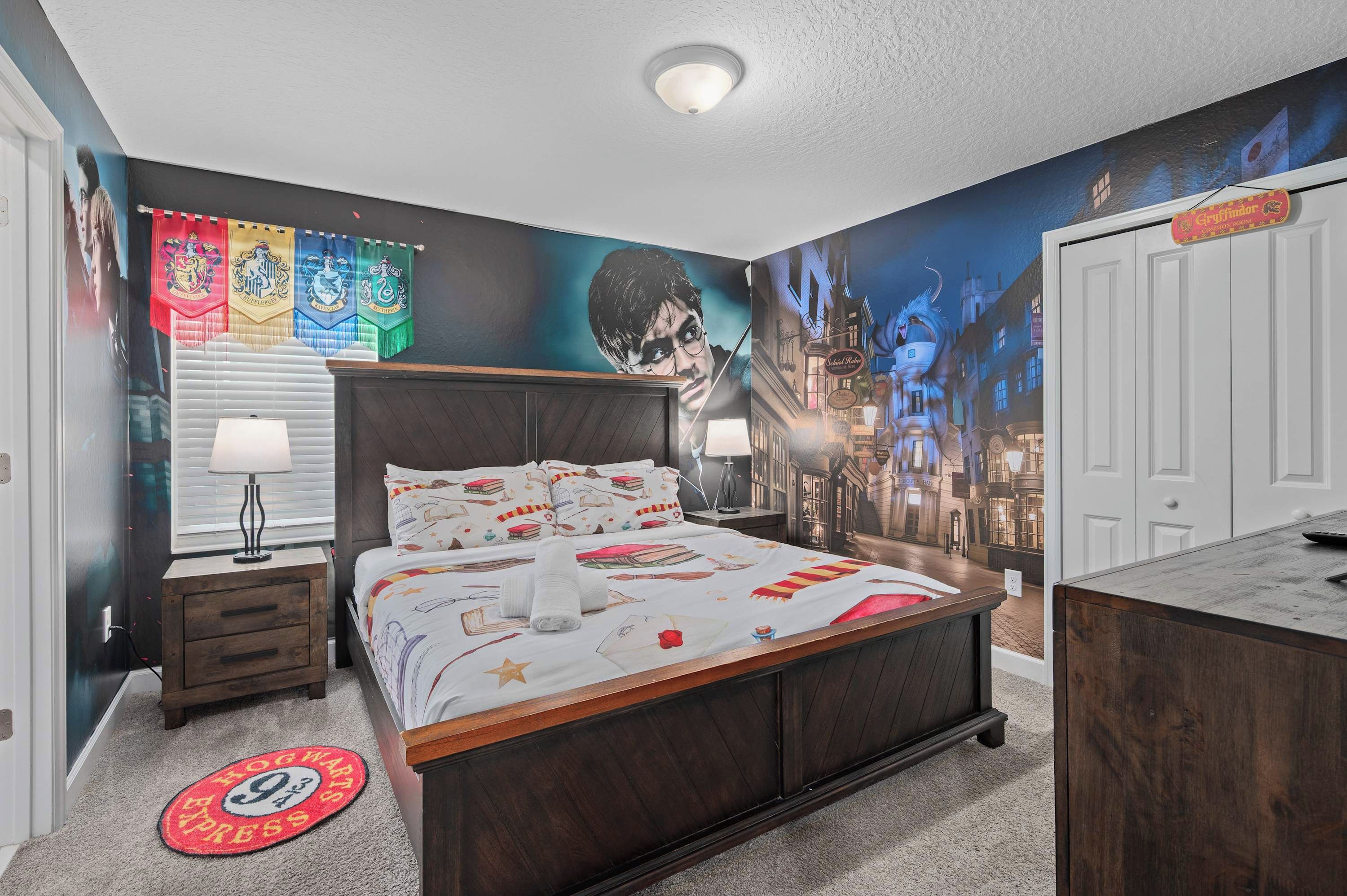 Une chambre avec un grand lit, une table de chevet, une commode et une fresque murale.