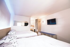Ett modernt hotellrum med två sängar, en TV som är monterad på väggen och en liten arbetsplats med skrivbord.