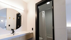 Un baño moderno con un lavamanos blanco, un grifo negro y un espejo grande.