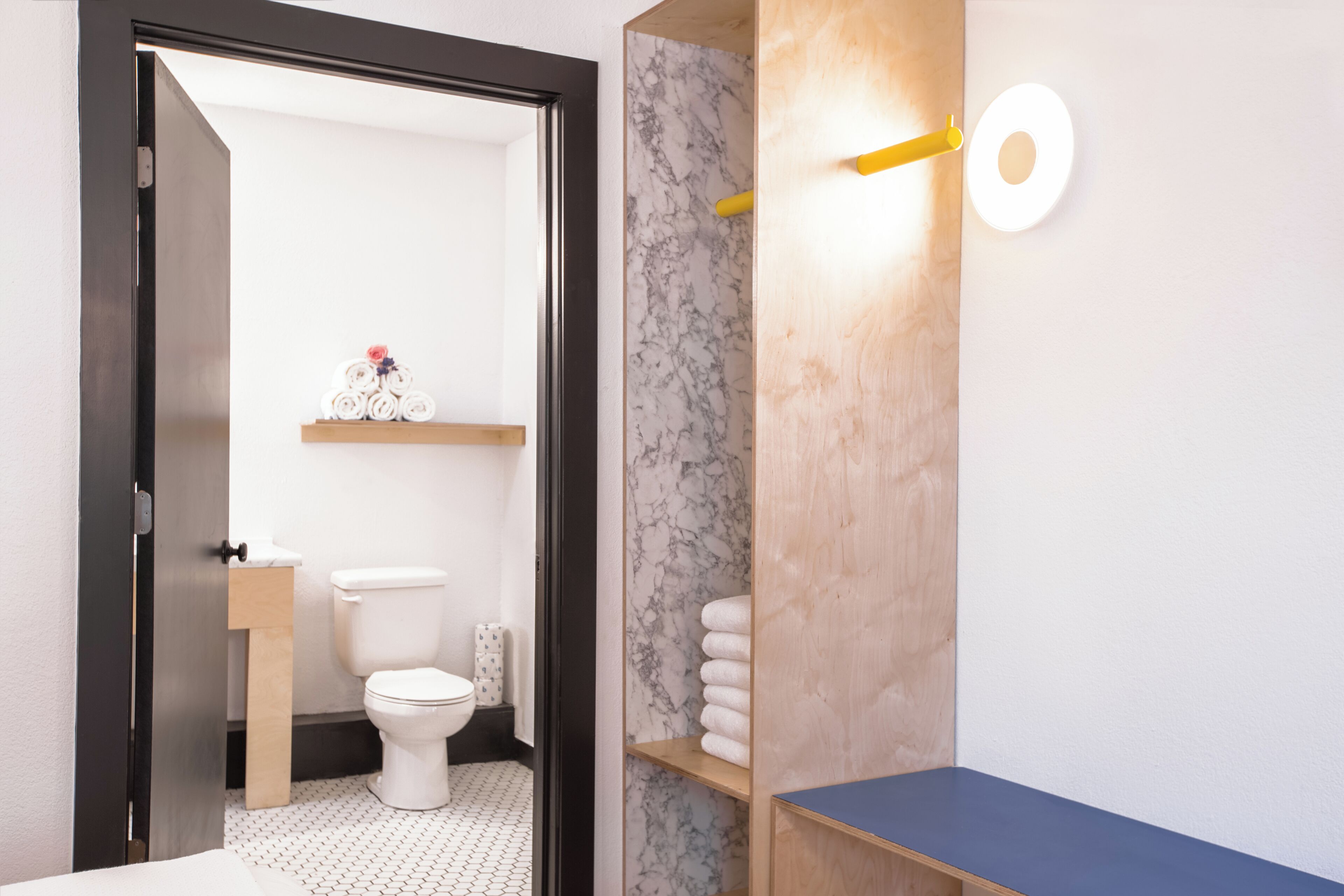 Ein modernes Badezimmer mit Toilette, Marmorwand, Holzregalen und einer blauen Ablagefläche.