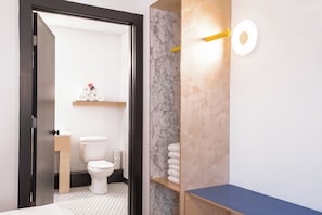 A modern bathroom with a toilet, marble wall, wooden shelves, and a blue countertop. - The Iris Motel - Queen Room (Nashville)