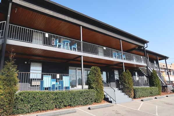 A two-story building with a balcony, stairs, and a parking lot.