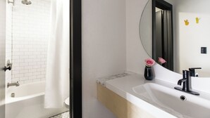 Un baño moderno con una bañera blanca, un espejo grande y un lavabo con grifo negro.