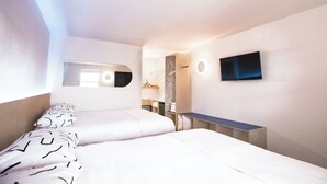 Moderni hotellihuone, jossa on kaksi sänkyä, seinälle asennettu televisio ja pieni työpöytä.