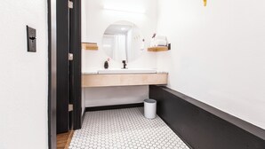 Un baño moderno con lavamanos blanco, espejo y suelo de baldosas hexagonales.