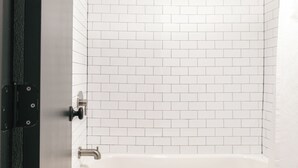 Un baño con una bañera blanca, ducha e inodoro.