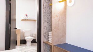 A modern bathroom with a toilet, marble wall, wooden shelves, and a blue countertop. - The Iris Motel - Queen Room (Nashville)