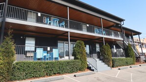 A two-story building with a balcony, stairs, and a parking lot. - The Iris Motel - Queen Room (Nashville)