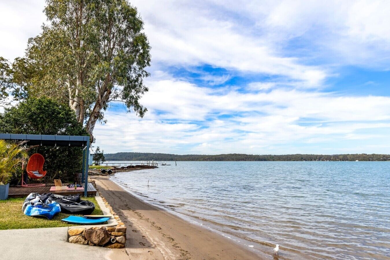 Une plage avec un espace de repos abrité, des kayaks et une mouette.