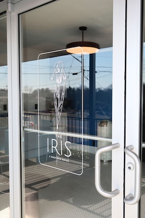 Una puerta de cristal con un logotipo y texto que indica 'The Iris Boutique Hotel'.